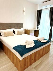 a bedroom with a large bed with two towels on it at Apartamente Victory Luxury Eforie Nord in Eforie Nord