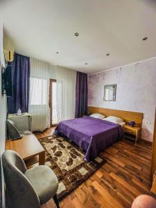 a bedroom with a purple bed and a chair at Vila Orange in Mamaia Nord