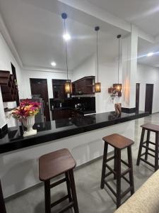 a kitchen with a black counter and two stools at DreamScape Holiday Apartment in Kalutara