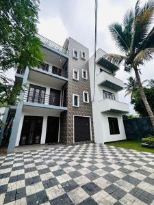 a large white building with a palm tree in front of it at DreamScape Holiday Apartment in Kalutara