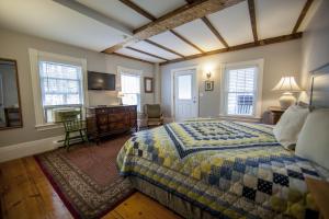 a bedroom with a bed and a desk and windows at Abalonia Inn in Ogunquit