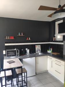 eine Küche mit weißen Schränken und einer schwarzen Wand in der Unterkunft City break in Cahors