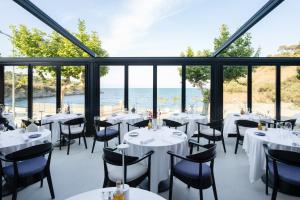 - un restaurant avec des tables et des chaises et une vue sur l'océan dans l'établissement Les Elmes - Hôtel, Spa & Plage Privée, à Banyuls-sur-Mer