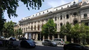 um grande edifício branco com carros estacionados em frente em beautiful apartment near opera in t'bilisi center em Tbilisi