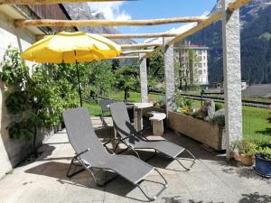 eine Terrasse mit 2 Stühlen und einem Tisch mit einem Sonnenschirm in der Unterkunft "Studio Edelweiss" Spillstatthus in Grindelwald