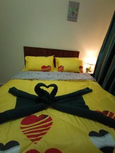 ein Bett mit einer gelben Decke mit Herz drauf in der Unterkunft Sofea Inn Bukit Merah - Laketown A6153 in Kampong Selemat