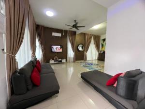 a living room with two black couches and red pillows at idaman hill homestay in Ipoh