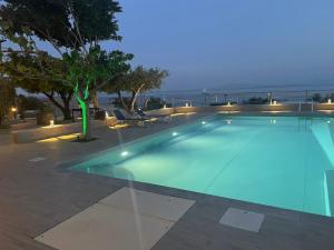 una piscina por la noche con el océano en el fondo en Magic View 4U katarina, en Kineta