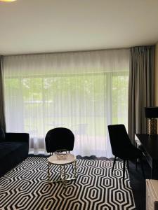 sala de estar con sofá, sillas y ventana en Apartament Solny Resort A032 z klimatyzacją, en Kołobrzeg