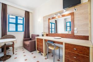 LivadiaにあるLivadia Beach Tilos Apartmentの鏡付きの洗面台と椅子が備わる客室です。