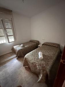 a bedroom with two beds and a window at CASA EN CAMPO DE GOLF CERCA DE LA PLAYA in Jerez de la Frontera