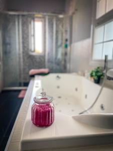 - un pot rose sur un comptoir dans une salle de bains avec baignoire dans l'établissement Belle maison familiale Basque, à Bayonne