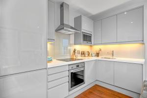 a white kitchen with white cabinets and a sink at JOIVY Tasteful flat with balcony in London
