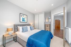 a bedroom with a large bed with a blue blanket at JOIVY Tasteful flat with balcony in London