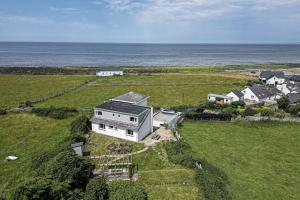 uma vista aérea de uma casa num campo com o oceano em Angorfa em Caernarfon