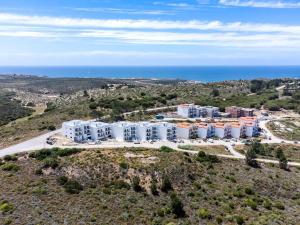 eine Luftaufnahme eines Gebäudes auf einem Hügel mit Blick auf das Meer in der Unterkunft Sun Sand Surf Apartment - Brand New & Cozy Apt in Aljezur in Aljezur