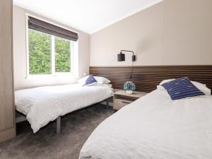 een slaapkamer met 2 bedden en een raam bij 63 The Maples in St Austell