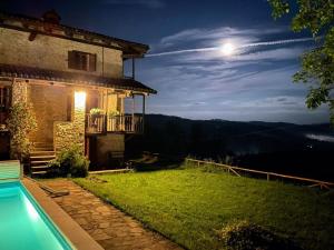 een huis met een zwembad in de nacht met de maan bij Cascina Manzoni appartamenti in Bossolasco