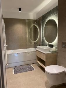 uma casa de banho com uma banheira, um WC e 2 espelhos em Charming 1-Bed Apartment in Brasov em Brasov