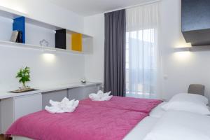 a bedroom with two white flowers on a pink bed at Rooms Kampus in Split