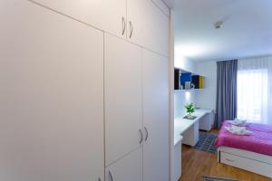 1 dormitorio con armarios blancos y 1 cama rosa en Rooms Kampus, en Split