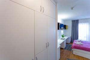 a bedroom with white cabinets and a pink bed at Rooms Kampus in Split