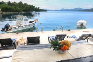 a table with a bowl of fruit and a boat in the water at Apartments Melany in Slano