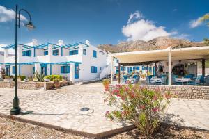 a white house with blue windows and a patio at Livadia Beach Suite in Livadia