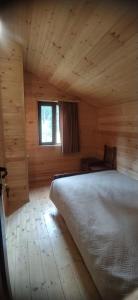 ein Schlafzimmer mit einem Bett in einer Holzhütte in der Unterkunft Tsemi My House in Bordschomi