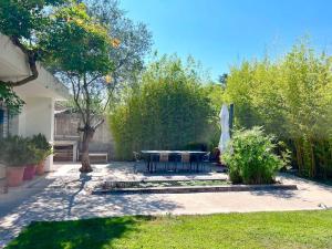 een patio met een tafel en stoelen in een tuin bij Charmante villa avec piscine et jardin paysagé in Le Crès