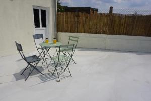 un patio con tre sedie e un tavolo con due bevande di Riva Cottage a Saint-Aignan