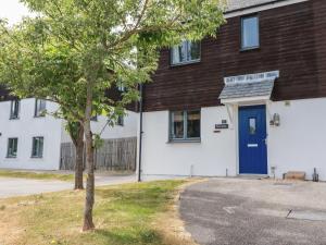 a white building with a blue door and a tree at Spinnaker in St Austell