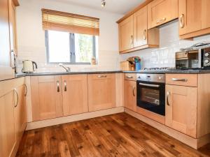 a kitchen with wooden cabinets and a sink at Spinnaker in St Austell