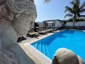 a pool with chairs and a statue next to it at Il FAUNO - Suite & SPA in Scafati