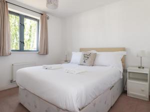 a white bed in a white bedroom with a window at Spinnaker in St Austell