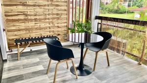 - une table et deux chaises sur une terrasse couverte avec un banc dans l'établissement L'ATELIEr COSY, à Cayenne