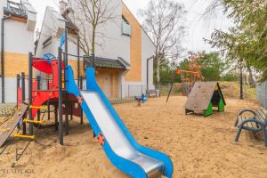 un parque infantil con tobogán y columpios en Flatbook Apartamenty - Jantar Park I, en Jantar