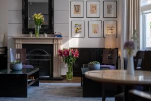 a living room with a fireplace and a table and flowers at K+K Hotel George Kensington in London