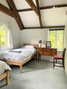 Un dormitorio con una cama, un escritorio y una silla. en Little Bosvathick, en Falmouth