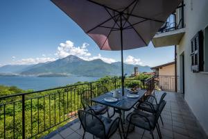 une terrasse avec une table, des chaises et un parasol dans l'établissement Agribenessere Brenzio, à Consiglio di Rumo