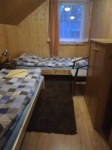 Cette chambre comprend deux lits, un bureau et une fenêtre. dans l'établissement AgroDana Malinka, à Wisełka