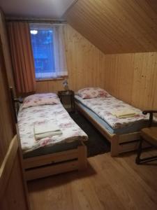 two beds in a small room with a window at AgroDana Malinka in Wisełka