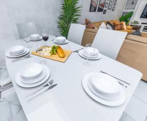 einen weißen Tisch mit weißen Tellern und Gläsern Wein in der Unterkunft Spacious and Comfy 6BD House - Ilford! in Ilford