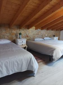 two beds in a room with a stone wall at Casa Emília & Alda in Juncal