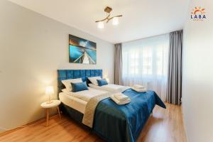 a bedroom with a king sized bed with blue sheets at LABA Kołobrzeg Apartamenty Zielone Tarasy in Kołobrzeg