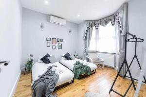 a white bedroom with two beds and a window at Spacious and Comfy 6BD House - Ilford! in Ilford