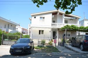 dos autos estacionados frente a una casa blanca en Apartmani "Nebo" en Sutomore