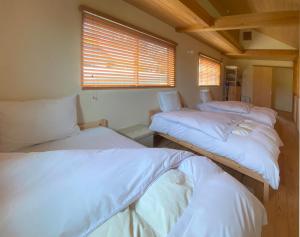 trzy łóżka siedzące w pokoju z oknem w obiekcie Garni MonyaMonya/ガルニモニャモニャ w mieście Hokuto