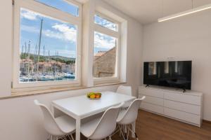 a white dining room with a white table and chairs at Apartment ACI Marina MILNA Brač in Milna