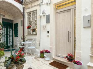 un patio con puerta, mesa y flores en Maison Chloe Perla Blanche, en Martina Franca